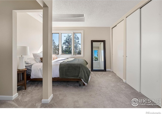 319 Camino Bosque, Boulder, CO 80302 - bedroom featuring light colored carpet, a textured ceiling, baseboards, and two closets