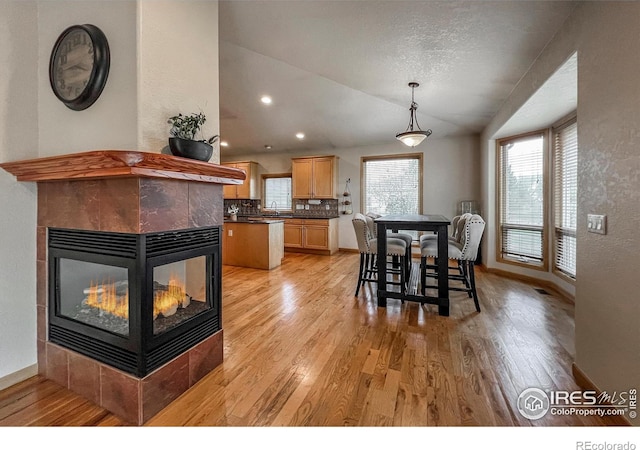 11669 Montgomery Cir, Longmont, CO 80504 - dining space featuring vaulted ceiling, light wood finished floors, and a tile fireplace