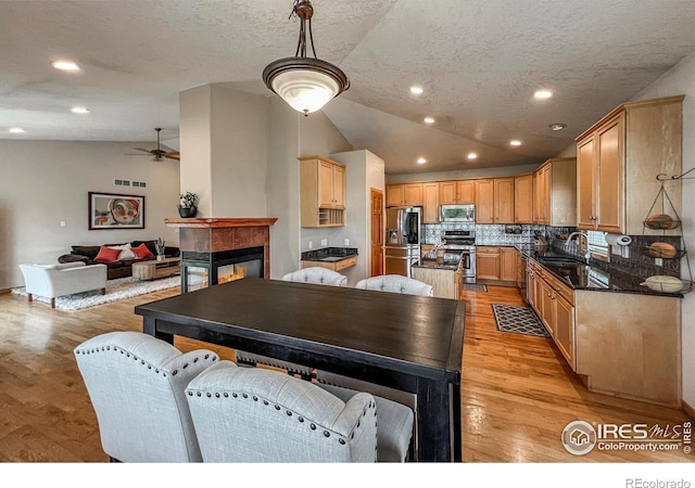 11669 Montgomery Cir, Longmont, CO 80504 - kitchen with ceiling fan, appliances with stainless steel finishes, light wood-type flooring, tasteful backsplash, and vaulted ceiling