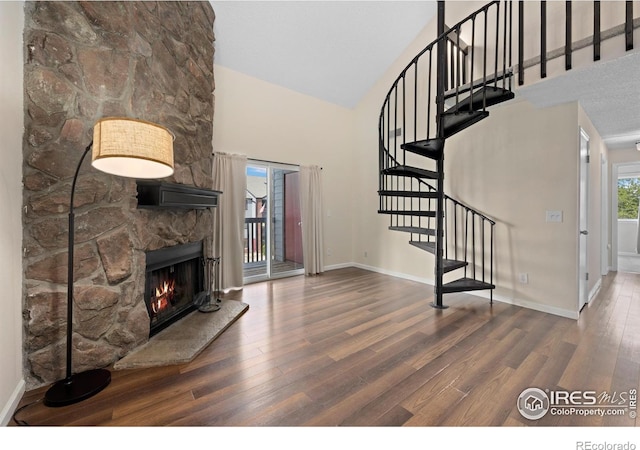 6385 Oak St Unit 301, Arvada, CO 80004 - living area featuring high vaulted ceiling, wood finished floors, a stone fireplace, and stairway