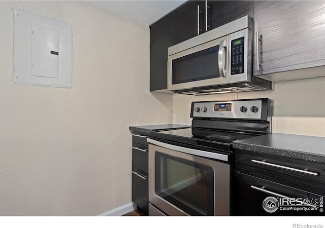 6385 Oak St Unit 301, Arvada, CO 80004 - kitchen with stainless steel appliances, electric panel, dark cabinetry, and dark countertops