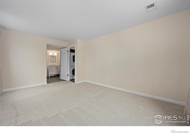 6385 Oak St Unit 301, Arvada, CO 80004 - unfurnished bedroom featuring stacked washing machine and dryer, carpet floors, and ensuite bathroom