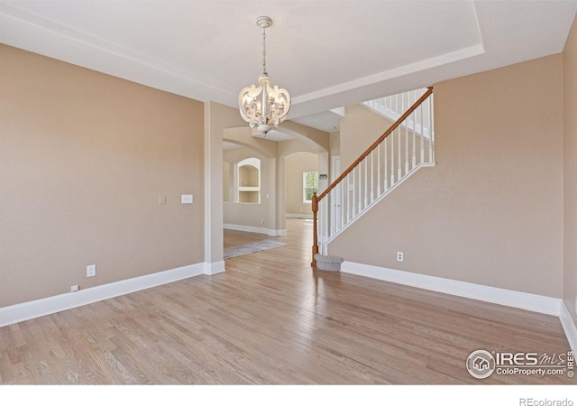 3530 Willow Rd, Frederick, CO 80504 - empty room with a notable chandelier, arched walkways, stairs, baseboards, and light wood-type flooring