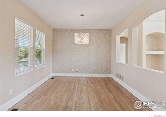 3530 Willow Rd, Frederick, CO 80504 - unfurnished dining area with an accent wall, baseboards, wallpapered walls, wood finished floors, and visible vents