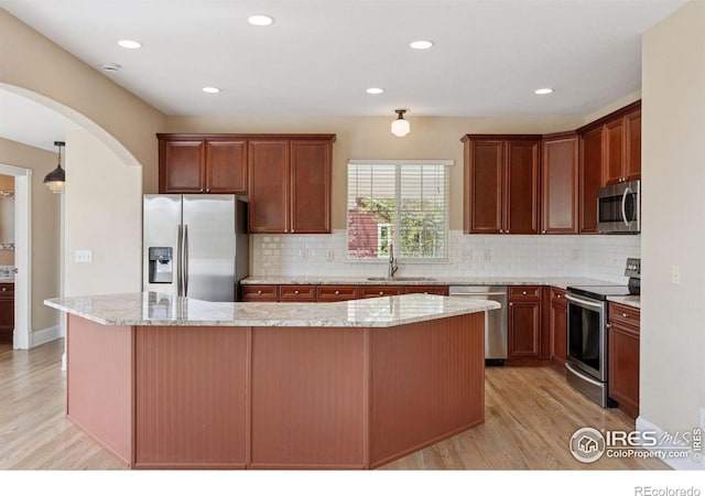 3530 Willow Rd, Frederick, CO 80504 - kitchen with stainless steel appliances, arched walkways, a sink, and light wood-style flooring