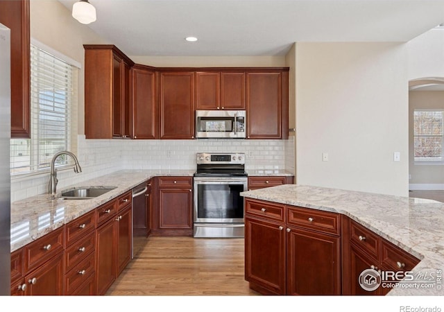 3530 Willow Rd, Frederick, CO 80504 - kitchen with light stone countertops, appliances with stainless steel finishes, a sink, light wood-style floors, and tasteful backsplash