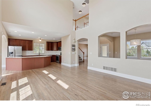 3530 Willow Rd, Frederick, CO 80504 - unfurnished living room featuring a high ceiling, stairs, baseboards, light wood-type flooring, and visible vents