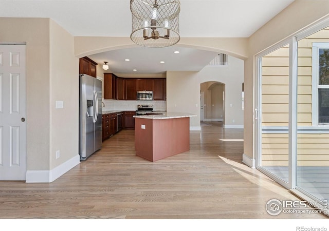 3530 Willow Rd, Frederick, CO 80504 - kitchen featuring light wood-style floors, a chandelier, arched walkways, appliances with stainless steel finishes, and backsplash