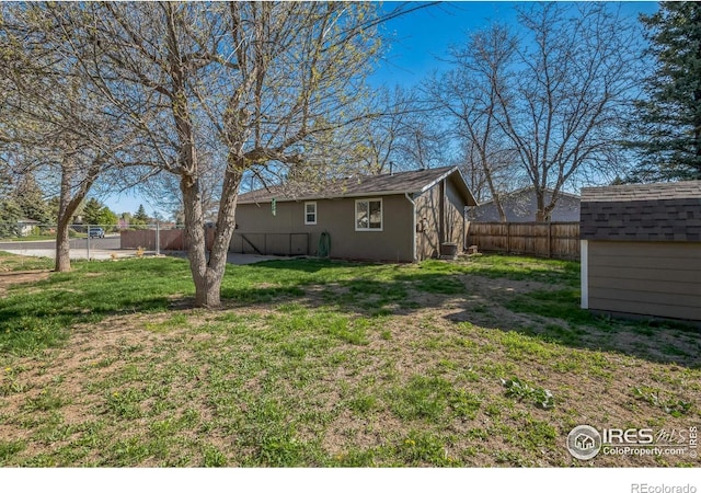 view of yard with a fenced backyard, a shed, and an outbuilding