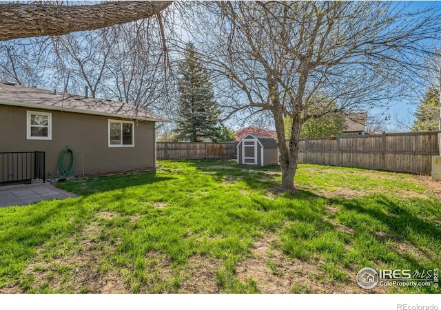 view of yard with an outdoor structure, a fenced backyard, and a storage unit