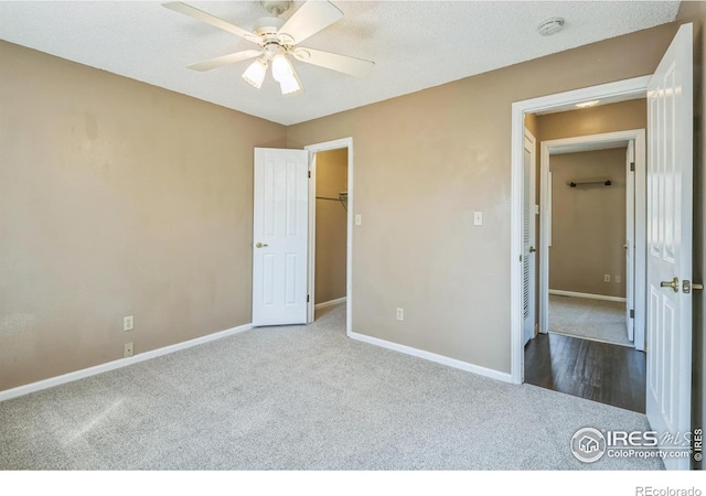 unfurnished bedroom with carpet floors, baseboards, a spacious closet, and ceiling fan