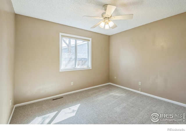 carpeted empty room with baseboards, a ceiling fan, a textured ceiling, and visible vents