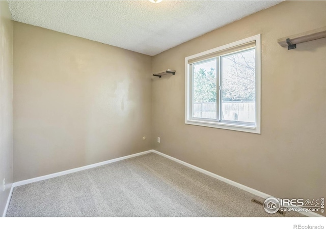 carpeted empty room with a textured ceiling and baseboards