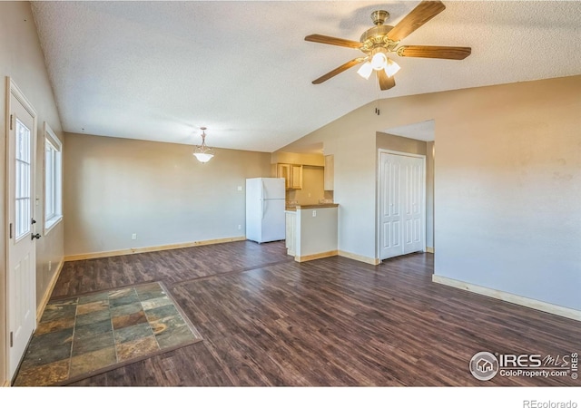 unfurnished living room featuring baseboards, ceiling fan, dark wood-style floors, a textured ceiling, and vaulted ceiling