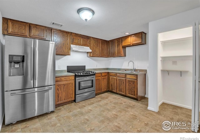 kitchen with visible vents, under cabinet range hood, brown cabinets, a sink, and stainless steel appliances