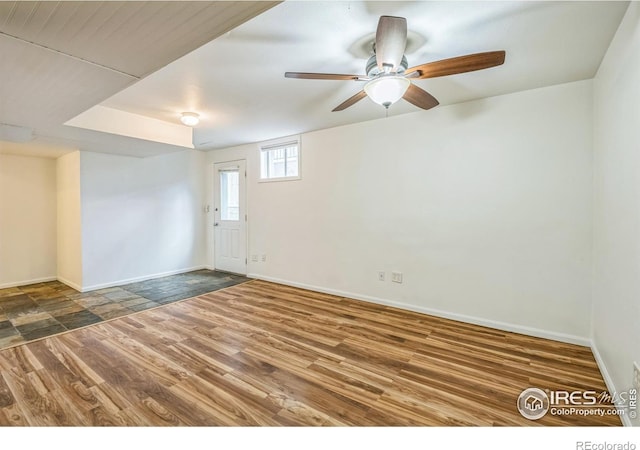 empty room featuring baseboards, a ceiling fan, and wood finished floors