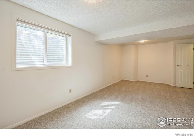 carpeted empty room featuring baseboards and a textured ceiling