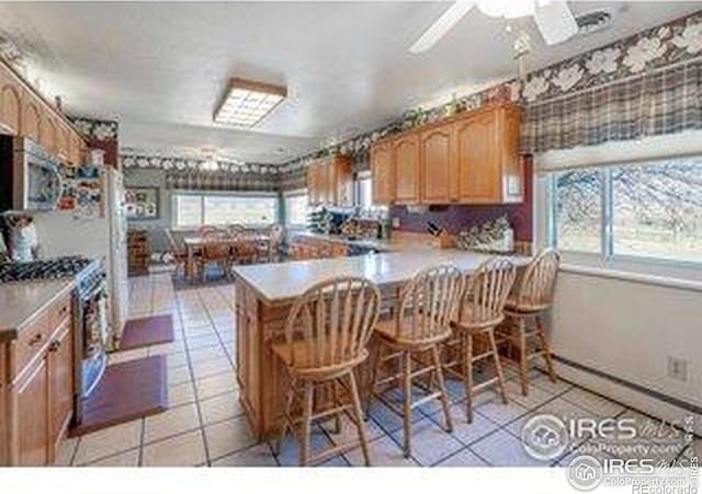 kitchen featuring a peninsula, stainless steel appliances, light countertops, and light tile patterned floors