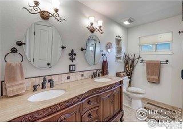 bathroom featuring double vanity, toilet, and a sink