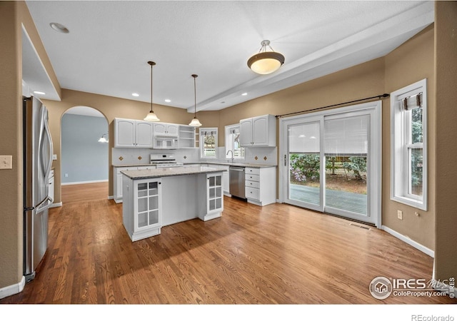2275 Schooner St, Lafayette, CO 80026 - kitchen featuring arched walkways, a center island, stainless steel appliances, and white cabinetry