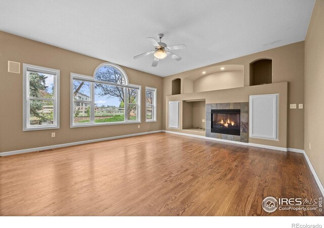 2275 Schooner St, Lafayette, CO 80026 - unfurnished living room with wood finished floors, baseboards, ceiling fan, built in shelves, and a tile fireplace