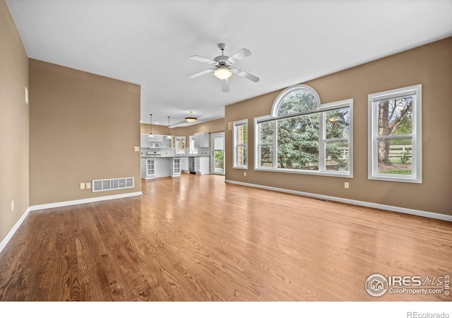 2275 Schooner St, Lafayette, CO 80026 - unfurnished living room featuring a ceiling fan, visible vents, a wealth of natural light, and wood finished floors