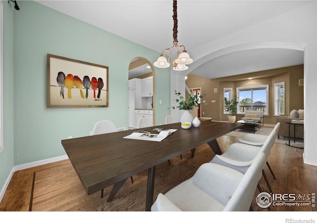 2275 Schooner St, Lafayette, CO 80026 - dining area featuring arched walkways, baseboards, a notable chandelier, and wood finished floors