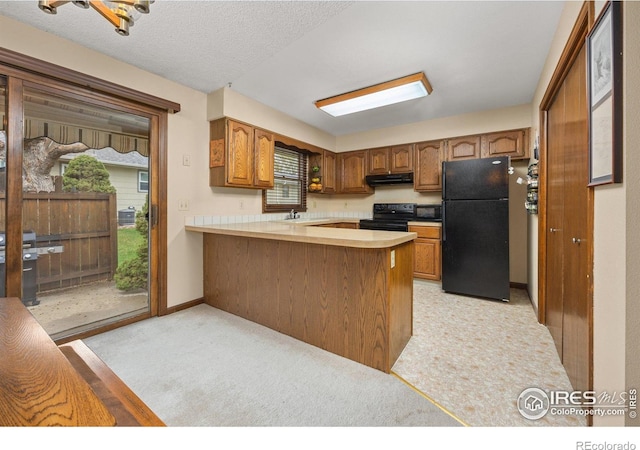 1183 38th Ave, Greeley, CO 80634 - kitchen with black appliances, a peninsula, brown cabinetry, light countertops, and under cabinet range hood
