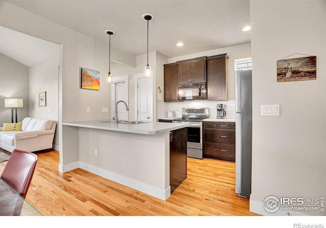 541 Hoyt Ln, Lafayette, CO 80026 - kitchen featuring dark brown cabinets, appliances with stainless steel finishes, a sink, open floor plan, and light wood-type flooring