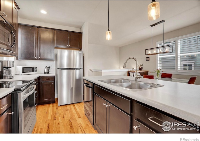 541 Hoyt Ln, Lafayette, CO 80026 - kitchen with dark brown cabinetry, appliances with stainless steel finishes, hanging light fixtures, a sink, and light wood-style floors