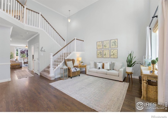 living area featuring wood finished floors, baseboards, a high ceiling, and stairs