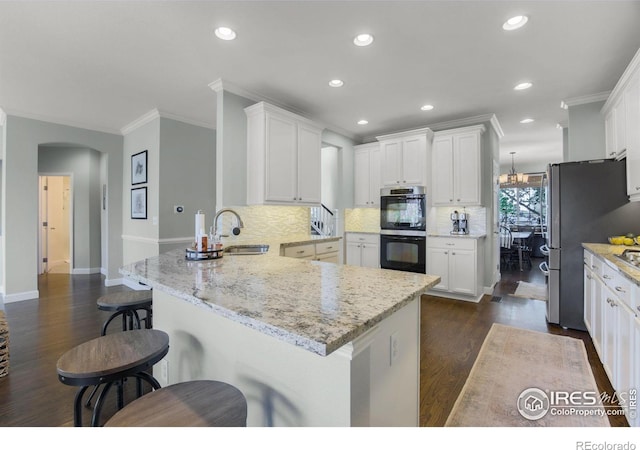 kitchen featuring a sink, a peninsula, freestanding refrigerator, ornamental molding, and dobule oven black