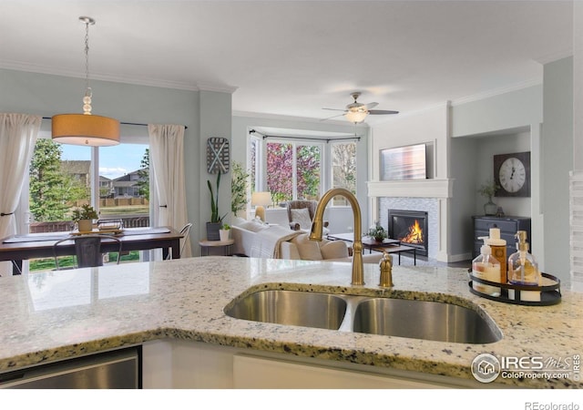 kitchen featuring light stone countertops, a glass covered fireplace, crown molding, and a sink
