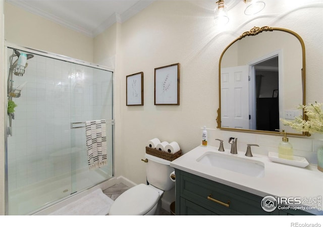 bathroom featuring vanity, toilet, a shower stall, and ornamental molding