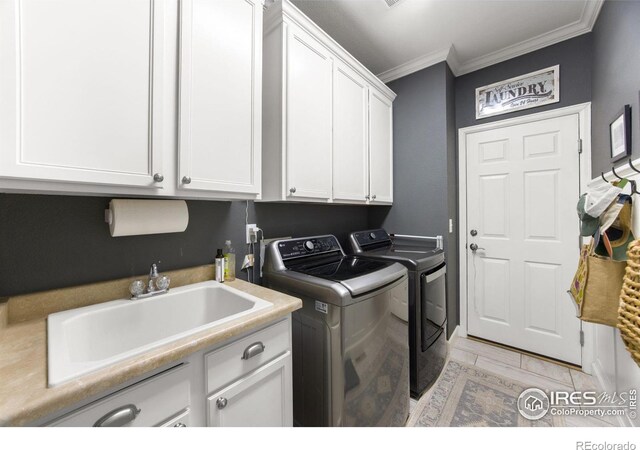 laundry room with cabinet space, washing machine and clothes dryer, crown molding, and a sink