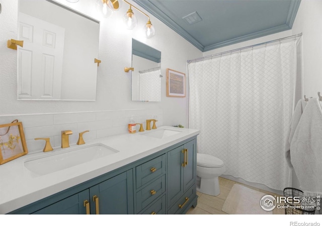bathroom featuring double vanity, toilet, ornamental molding, and a sink