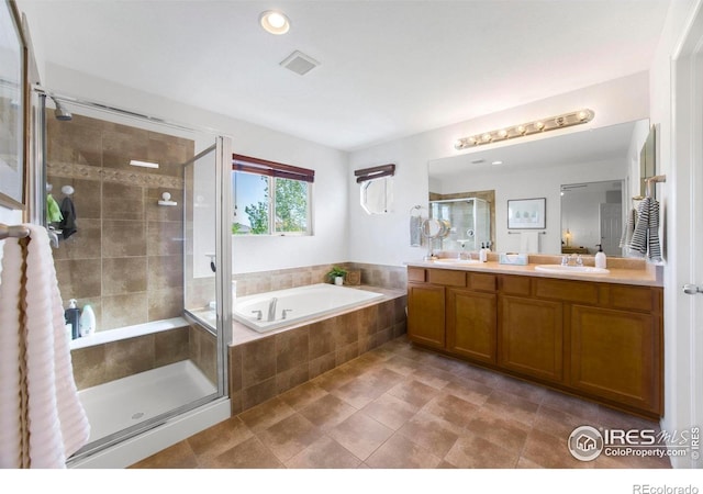 full bathroom with a stall shower, visible vents, a sink, a garden tub, and double vanity