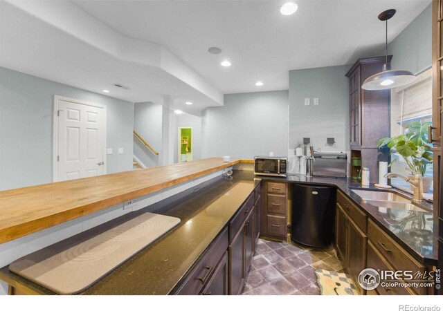 kitchen with stainless steel microwave, a sink, dishwashing machine, recessed lighting, and pendant lighting