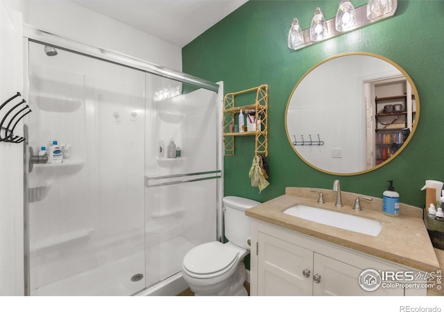 bathroom featuring vanity, toilet, and a shower stall