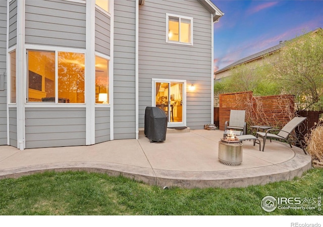 back of property at dusk with an outdoor fire pit and a patio area