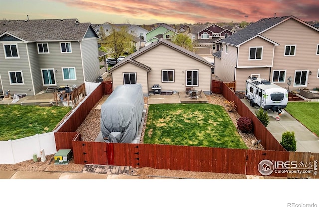 6659 12th St, Frederick, CO 80530 - back of property at dusk featuring a yard, a residential view, a fenced backyard, and a patio area