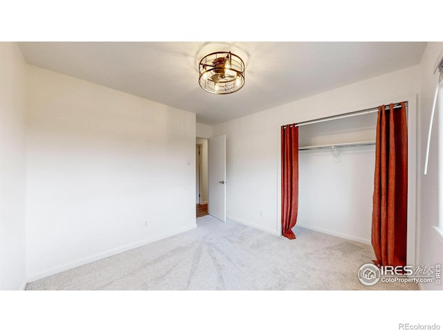 unfurnished bedroom featuring baseboards, carpet, and a closet