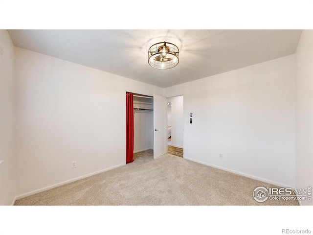 unfurnished bedroom featuring baseboards, light colored carpet, and a closet