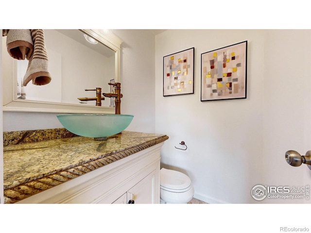 half bath featuring vanity and toilet