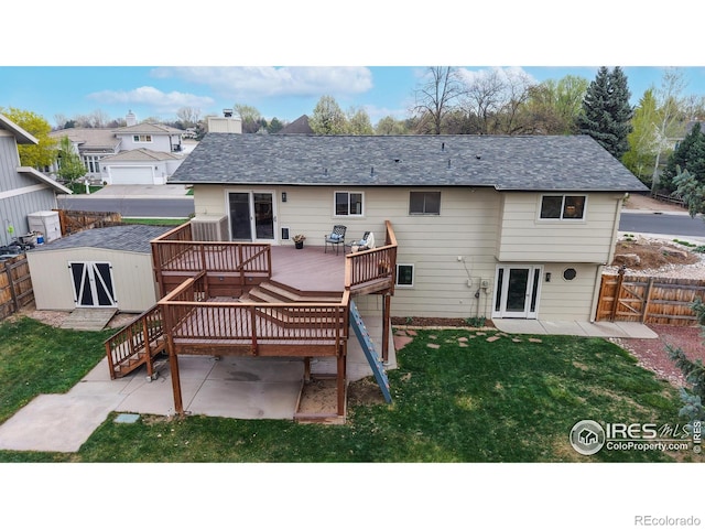 back of house featuring a yard, a wooden deck, a fenced backyard, and a shed