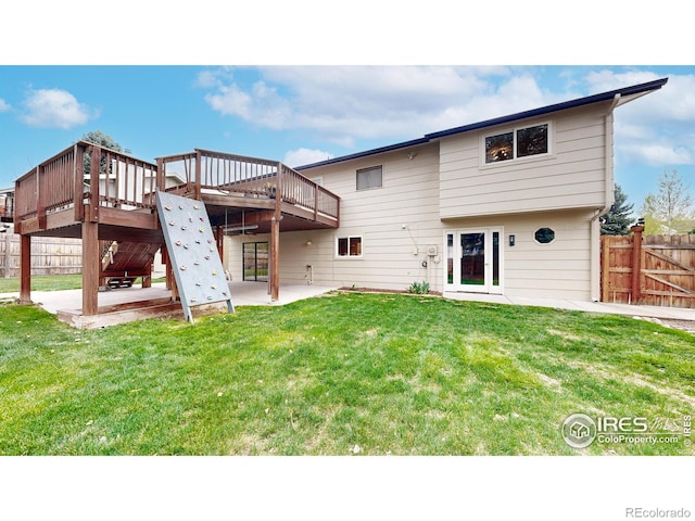 rear view of property with fence, a lawn, a patio area, and a deck