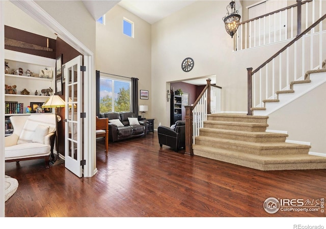 foyer entrance featuring stairs, a towering ceiling, and wood finished floors