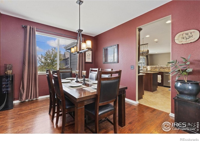 dining room featuring baseboards, a notable chandelier, a textured wall, and wood finished floors