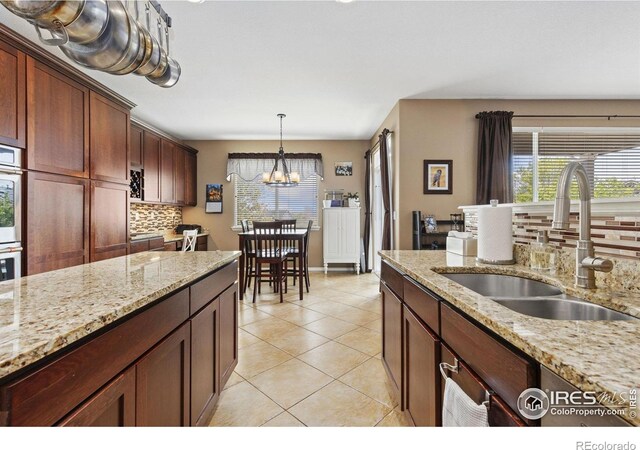 kitchen with a sink, light tile patterned floors, tasteful backsplash, and plenty of natural light