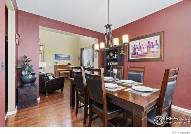 dining room featuring baseboards, a textured wall, and wood finished floors